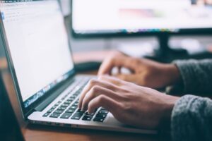 Person typing on a laptop at a wooden table, representing nostalgic tech content